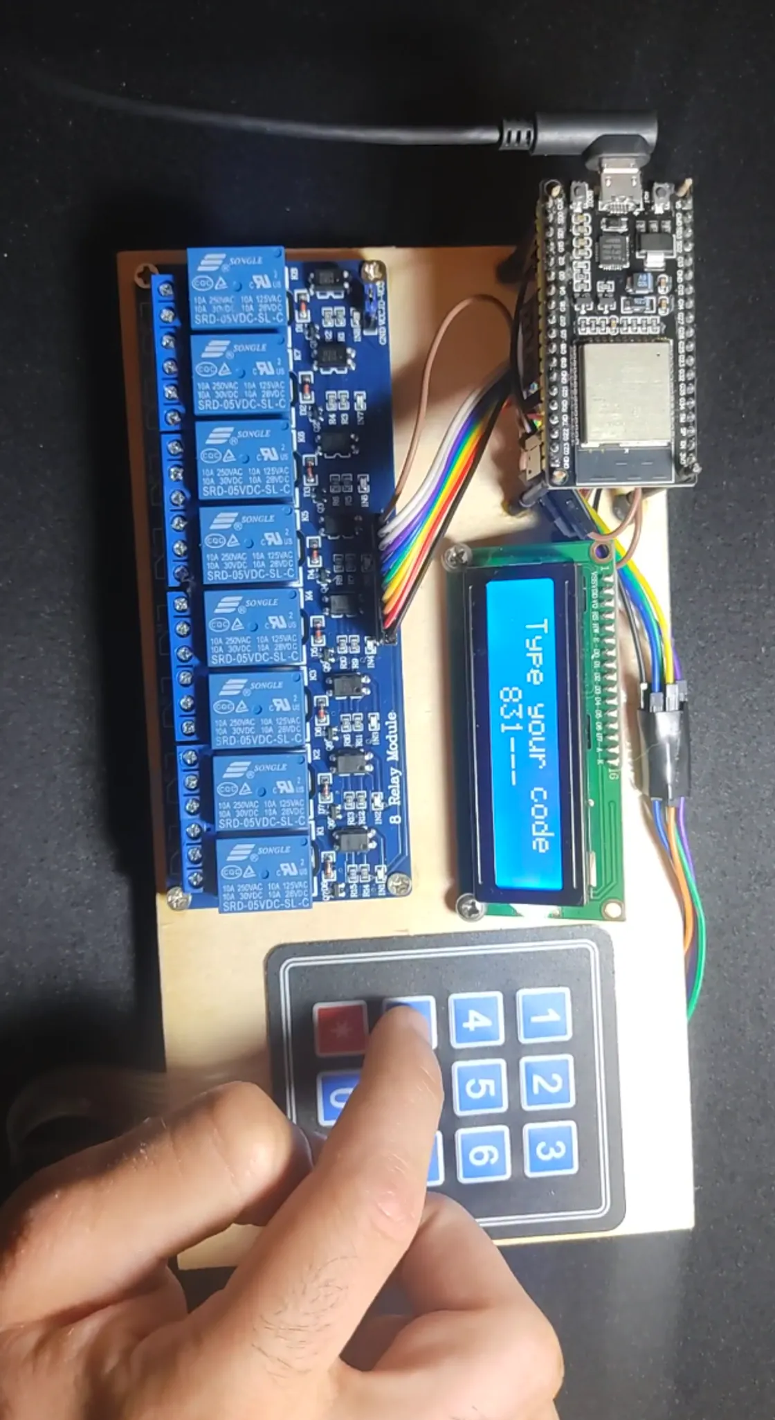 Gestire's assembled controller with an ESP32, eight-channel relay board, LCD and a hand entering a code on the keypad.
